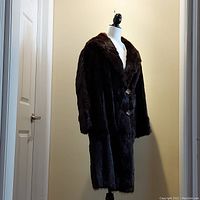 Full front view of full-length brown fur coat on mannequin