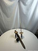 Two decorative rapiers standing upright with a single antique sword lying flat on a table, green apple for size reference.