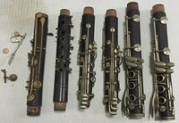 Five clarinet barrels and middle joints with brass keys and cork ends, arranged side by side showing condition.
