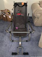 Front view of AB Lounge Ultra exercise chair showing mesh seat with logo, tubular steel frame, and foot pedals.