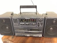 Front view of Emerson boom box and detachable speakers with control panel, buttons, and speaker grills visible.