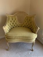 Front view of French provincial style armchair showing tufted pale green velvet upholstery, carved wooden frame, and rattan back panel.