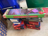 Box of 4 candy cane light stakes with red and white striped design in original packaging, set on top of piled boxes in a garage setting.