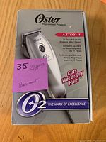 Front view of Oster Aztec 11 hair clipper box showing product image and key features on label.