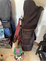 Golf clubs in tartan and black bags next to golf balls and tees in garage setting