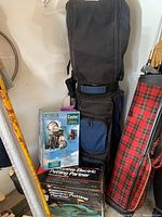 Overview photo showing golf cooler box, World of Golf putting partner box, and golf bag with clubs standing upright.