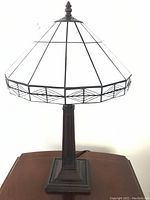 Front view of the lamp showing the white leaded glass style shade and the dark metal base.