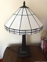 Front view showing full lamp with metal base and white leaded glass style shade.