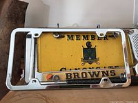 Chrome license plate frame with "BROWNS" text and small Cleveland Browns helmet logo inside a rectangular frame.