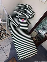 A full green and white striped lounger cushion with several pillows placed on top, showing the pattern and size of the cushions.