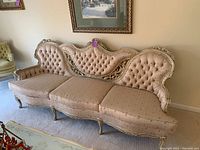Side view of French provincial sofa showing tufted back and ornate wooden frame detail