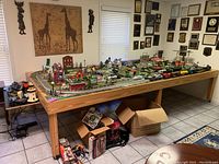 Wide view of layout on wooden table with tracks, buildings, vehicles and trees