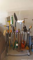 Photo of Suncast beige plastic wheeled tool caddy filled with various garden tools including broom, shovel, and hand tools in garage setting.