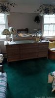 Full view of nine-drawer dresser with items on top and wall mirror above.