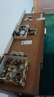 Wide view of three boxes on a wooden table containing assorted earrings and bracelets
