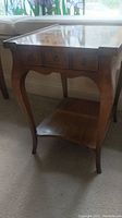 Front and side view of wooden end table showing drawer and curved legs with lower shelf