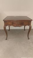 Front view of wooden end table showing dovetail drawer and cabriole legs