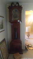 Full front view of the wooden tall case grandfather clock showing bonnet, trunk and base
