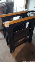 Photo of one saw horse showing yellow top edge, black base, and foldable mechanism.