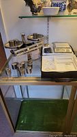 Mechanical balance scale with metal weights displayed on glass shelf.