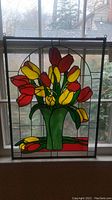 Straight-on view of full stained glass panel showing red and yellow tulips in green vase