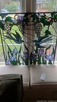 Full frontal view of stained glass panel hung in window under natural light