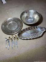 Bowl, round tray, leaf-shaped tray and spoons arranged on carpet