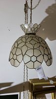 Clear view of the entire capiz swag lamp hanging with chain and pull chain visible.