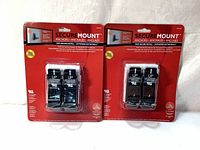 Two packages each containing 2 SecureMount anchors displayed on light fabric background, showing front of packaging.