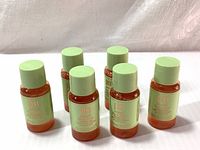 Six small travel size 15ml bottles of PIXI Glow Tonic Exfoliating Toner with green caps arranged on a surface.