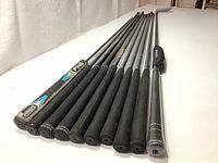 Photo showing the ends of 11 golf club shafts lined up, with grips and various brand markings visible on the shafts and grips.
