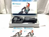 View of opened packaging box showing the iQ Motion gimbal stabilizer inside with the product manual underneath, showing the main gimbal handle and clamp section separated by a support.