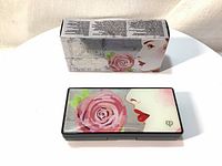 Closed lip color palette box and compact with floral and woman's face design on the lid