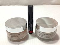 Front view of three Marcelle products: Night Cream (left), Extension Plus Curl Mascara (center), Moisture Cream (right), showing product names and jar design