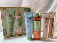 The three PIXI Skintreats skincare products shown alongside their original box packaging, including Clarity Cleanser, Glow Tonic, and Peel & Polish tubes and bottle.