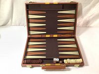 Open vintage backgammon game case revealing the playing surface and arrangement of checkers and dice.