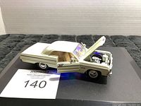 White 1964 Chevy Impala pullback model car showing open left door and hood with visible engine detail on black display base.