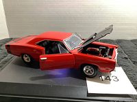 Left side angled view of red 1969 Dodge Coronet Super Bee model car showing open driver door and raised hood revealing detailed engine bay.