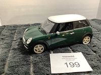 Green and white Mini Cooper model with closed doors and roof visible.