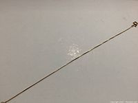 Photo of full length of thin 10k gold bracelet on white background showing the chain style and color