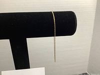 Long view of the fine twisted chain bracelet on a black display stand to show length and delicate style.