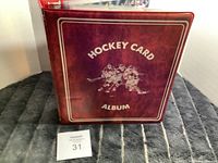 Front cover of a red hardcover hockey card album titled 'Hockey Card Album' with a graphic of three hockey players.