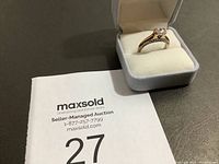 Estate ring in grey velvet ring box on a gray surface alongside a MaxSold auction number card