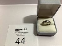 Ring displayed in an open light grey velvet ring box on a white surface with MaxSold auction paper labeled 44.