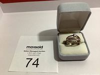 The estate ring with clear gemstone on top of multiple intertwined bands in a grey velvet ring box.