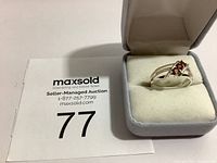 Ring shown in gray cushioned ring box with auction tag visible.