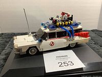 Full side view of white Lego Ghostbusters Ecto-1 vehicle with Ghostbusters logos and roof accessories.