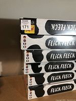 Stack of six sealed Flick Fleck game boxes showing branding and packaging