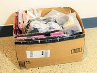 Box of various new soft items including fitness, pet and bag products all packaged inside a cardboard box.