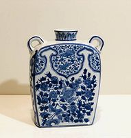 Front view of the vase showing blue floral and bird motifs with two small handles near the neck and short neck with rim.